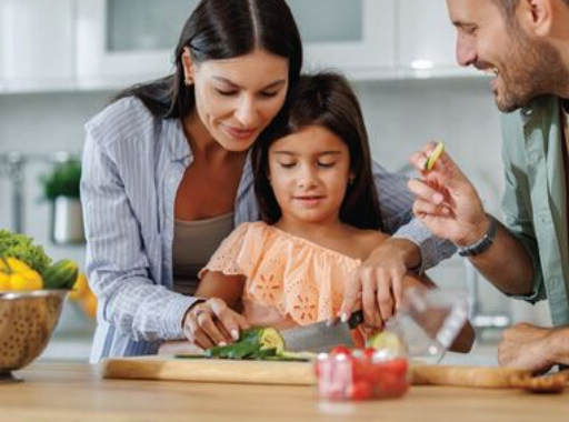 A mother, father and daughter preparing vegetables together in their kitchen